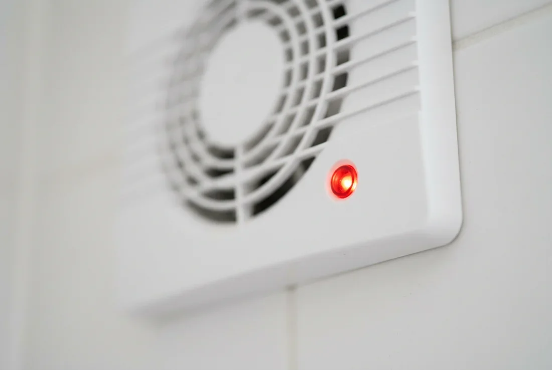 Extracteur d'air Silent 100 Design en fonctionnement VMC Silent 100 Design blanche installée au mur d'une salle de bain moderne avec voyant rouge allumé