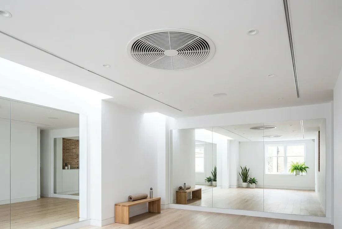 Bureau de luxe dans un sous-sol aménagé et lumineux avec une bouche de ventilation discrète au plafond.